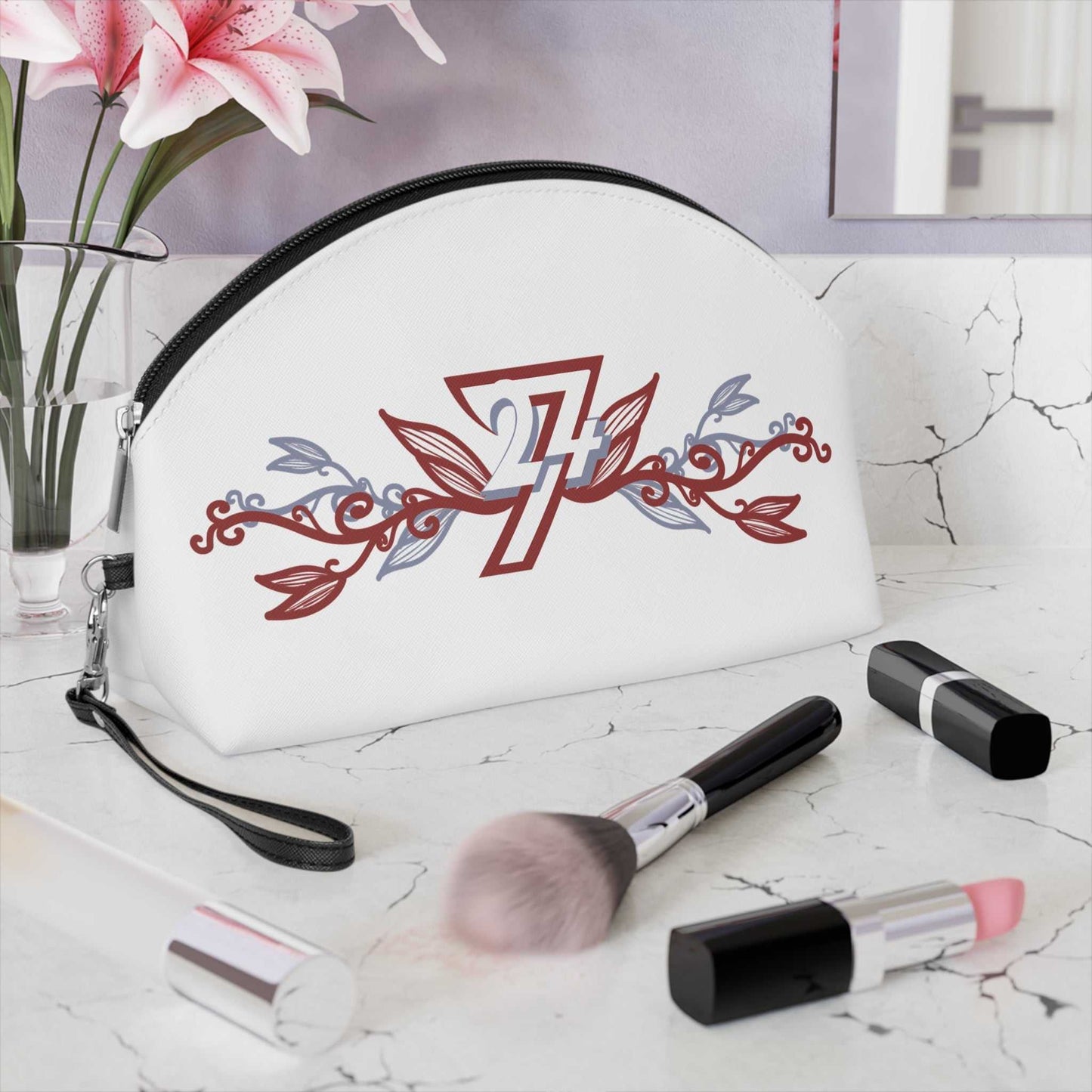The elegant floral makeup bag by 24/7 Unique Designs sitting gracefully on a white marble bathroom vanity, surrounded by a makeup brush, lipstick, and fresh flowers to showcase its chic aesthetic.