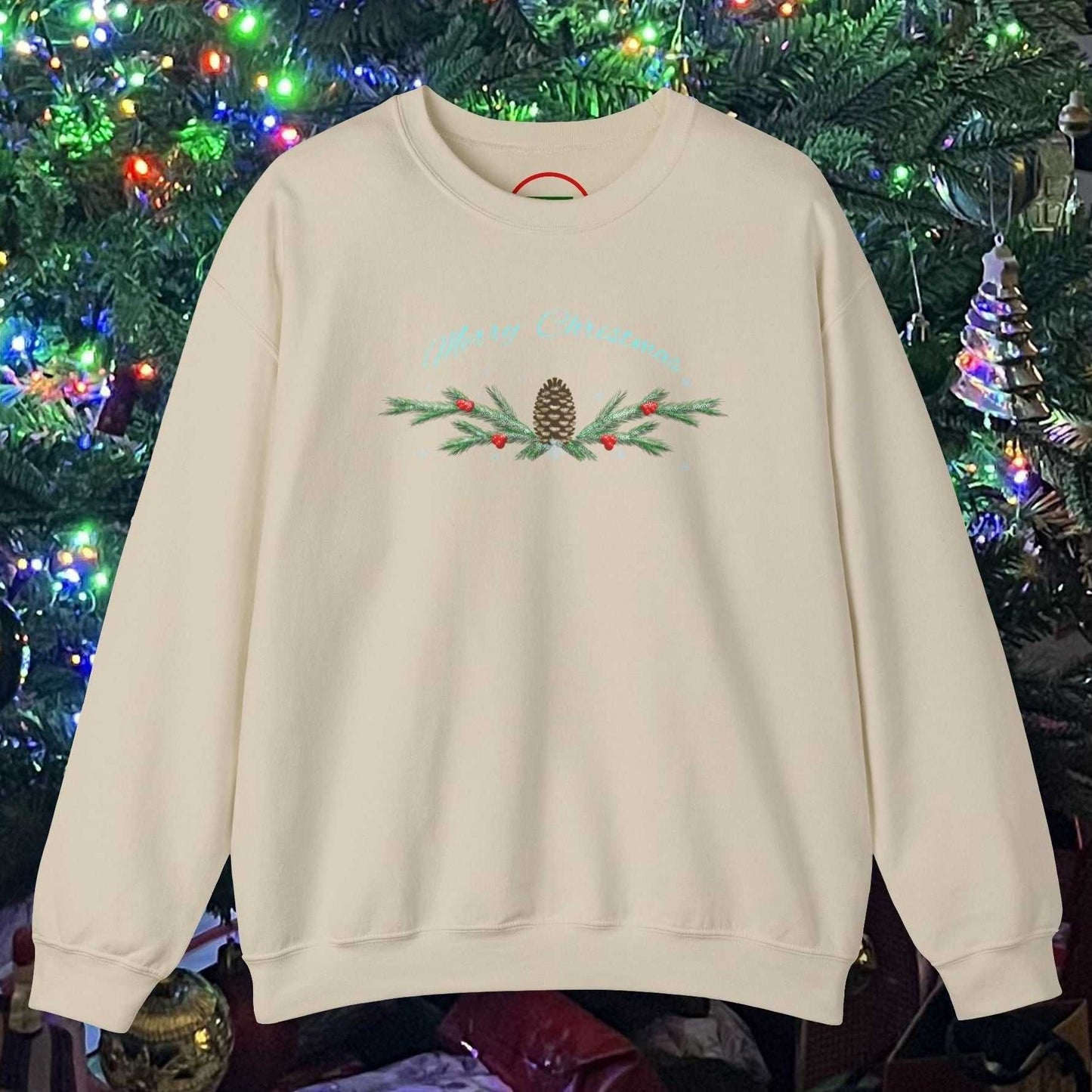 Beige Pinecone Christmas sweatshirt with hand-drawn pinecone and branches design in front of decorated Christmas tree lights