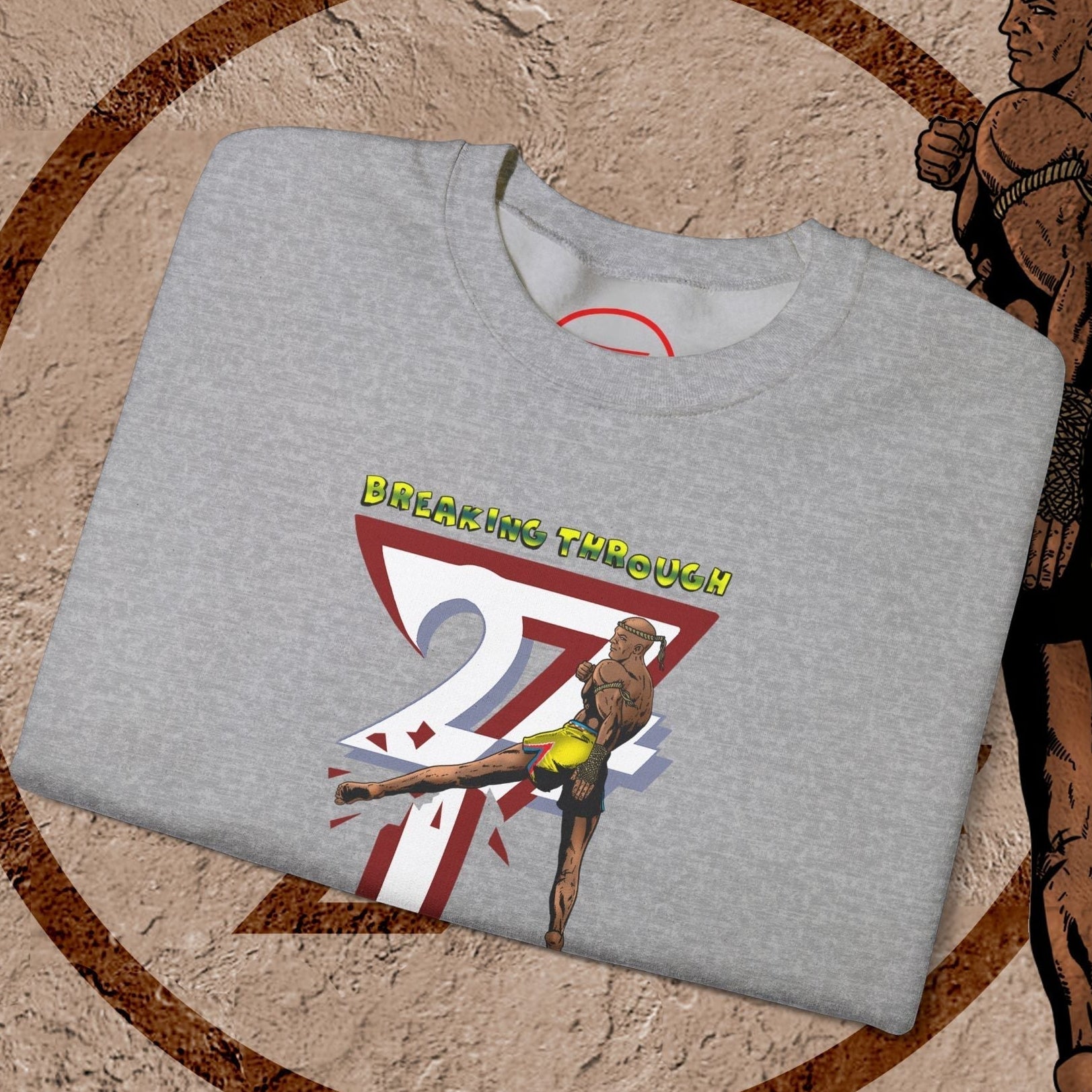 Gray Muay Thai sweatshirt with vibrant hand-drawn fighter design and "Breaking Through" text, made from cotton-polyester blend.