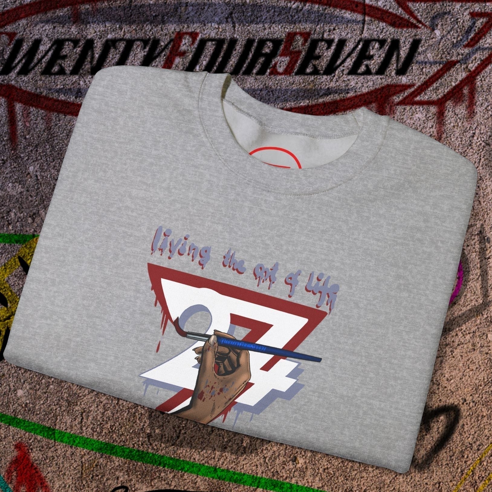 Gray artist brush sweatshirt with hand-drawn bohemian design laid on graffiti background