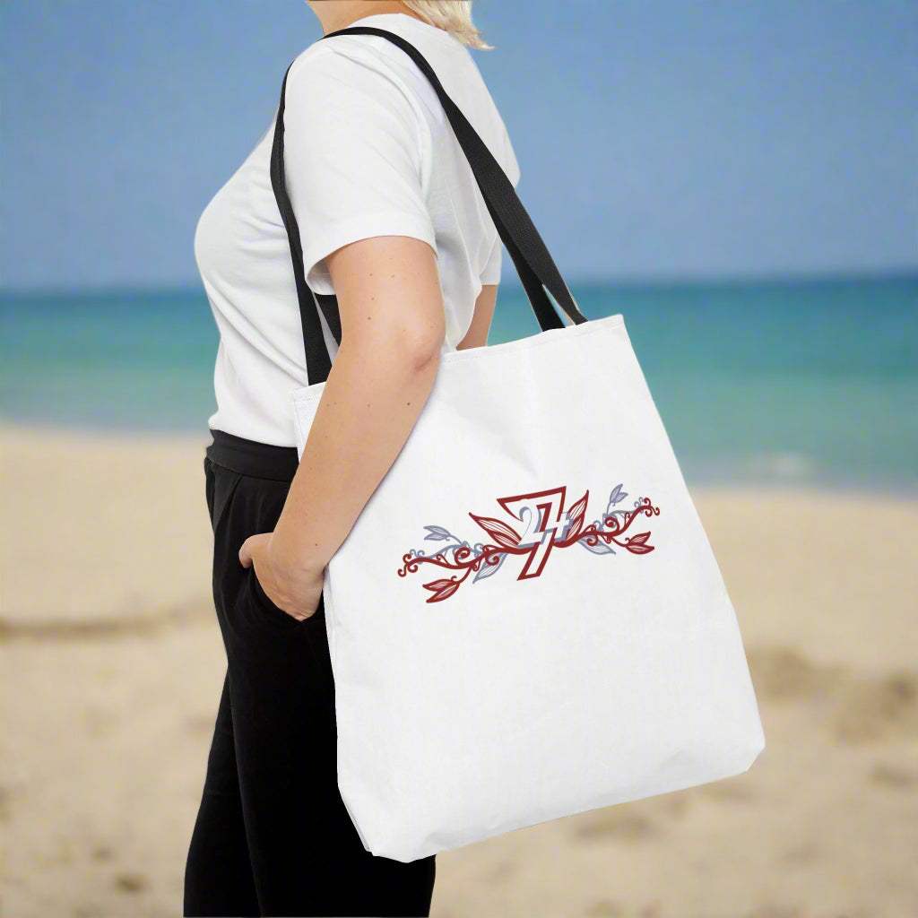 Large stylish tote bag with flower design and 24/7 trademark logo on woman walking on a sandy beach