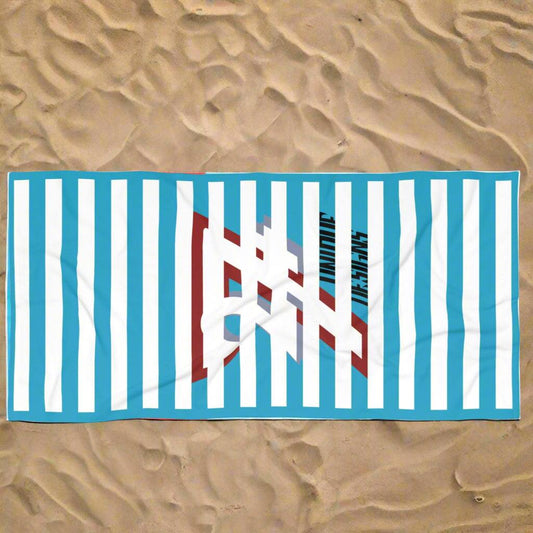 Oversized pool towel laid out on the beach sand ready for summer lounging.