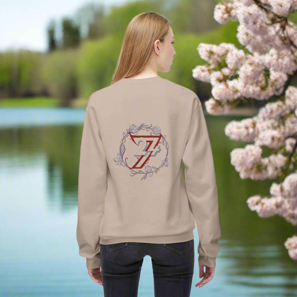 Woman facing away modeling a slouchy beige sweater with a massive flower design on the back.
