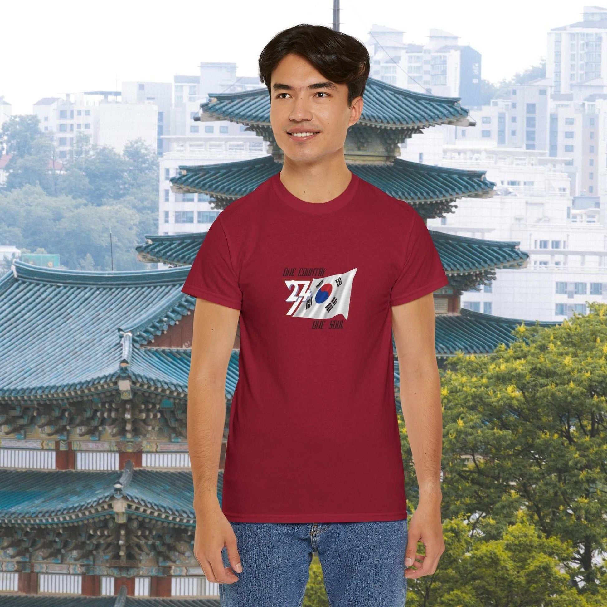 man wearing red South Korea flag graphic tee with hand-drawn Taegeukgi design standing in front of traditional Korean architecture