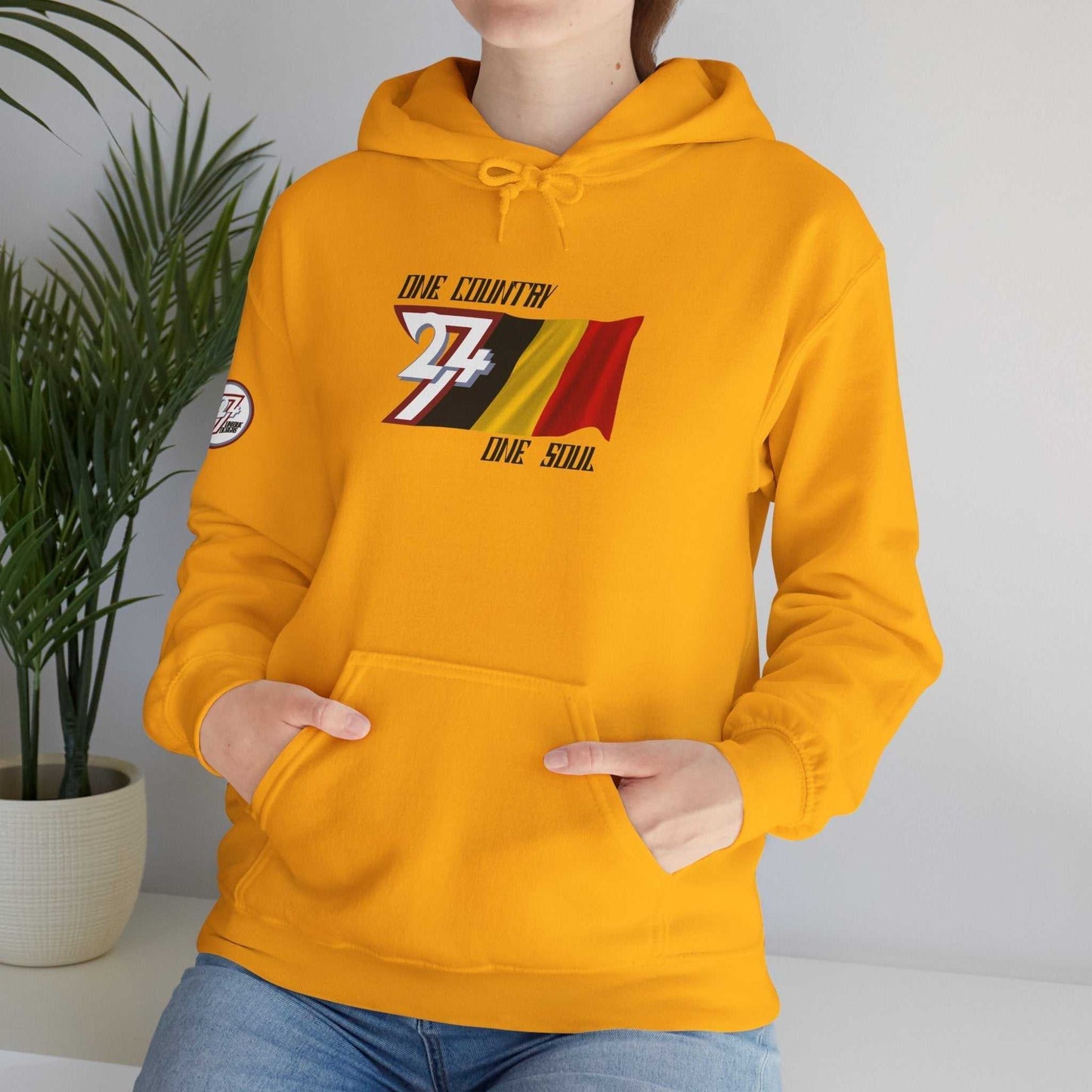 Model wearing the België "Colloquy" hoodie in Gold, styled for a modern streetwear look.