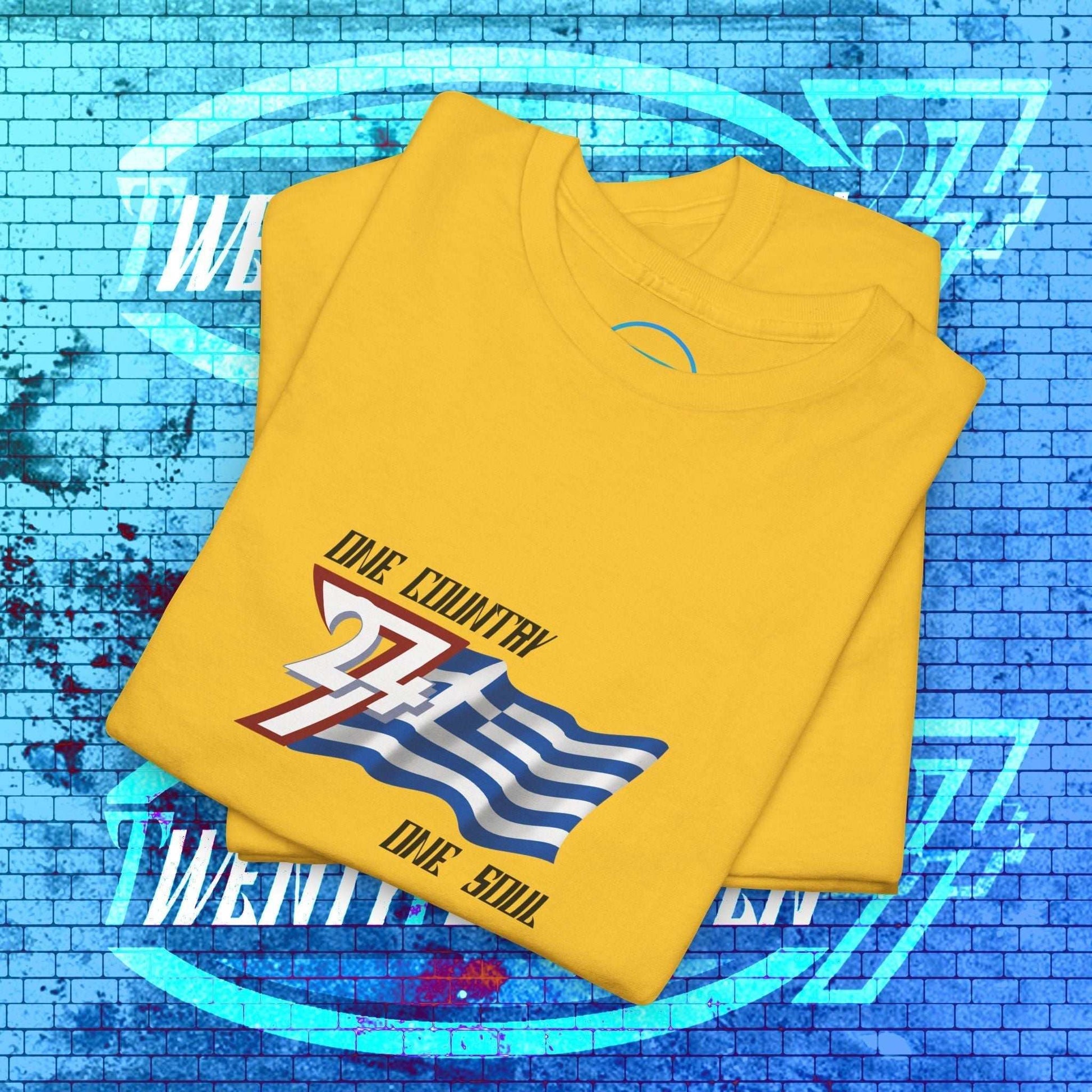 Neatly folded yellow cotton tee showing the hand-drawn Greek flag illustration and "One Country One Soul" text for gifting.