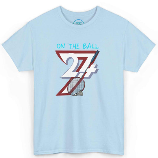 Front view of a light blue comic-style badminton graphic tee featuring the digitally hand-drawn On the Ball art, displayed on a clean background.