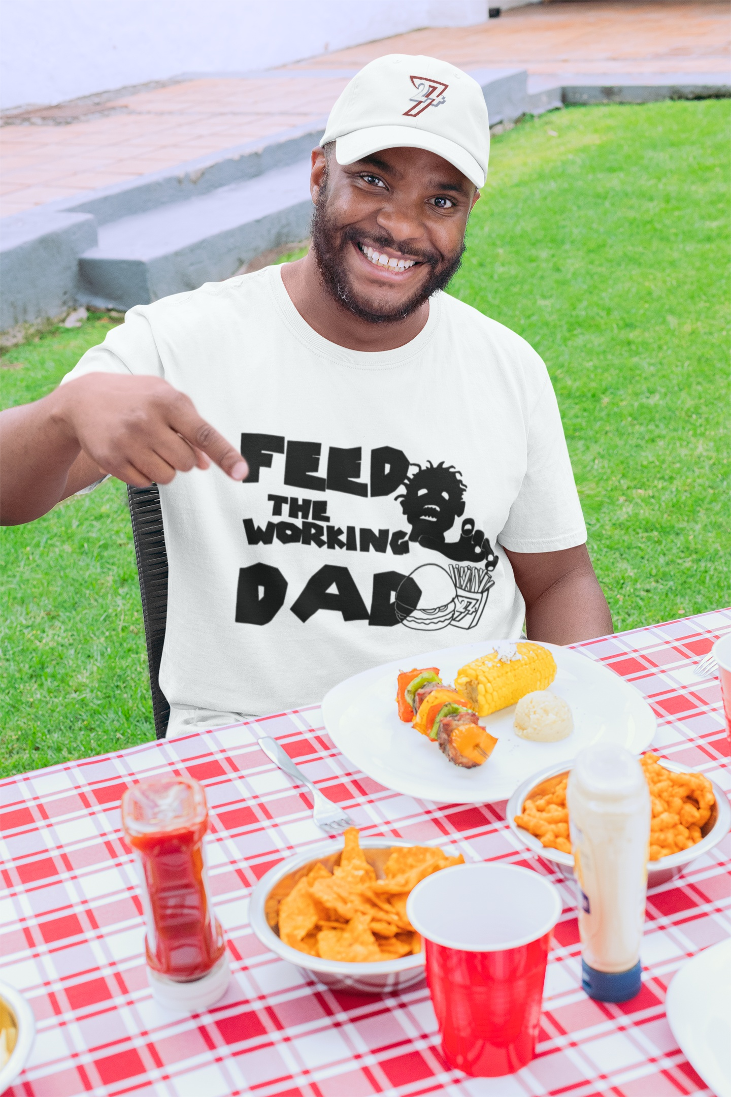 Male model wearing the white funny zombie dad graphic tee to showcase the relaxed fit at a picnic table.