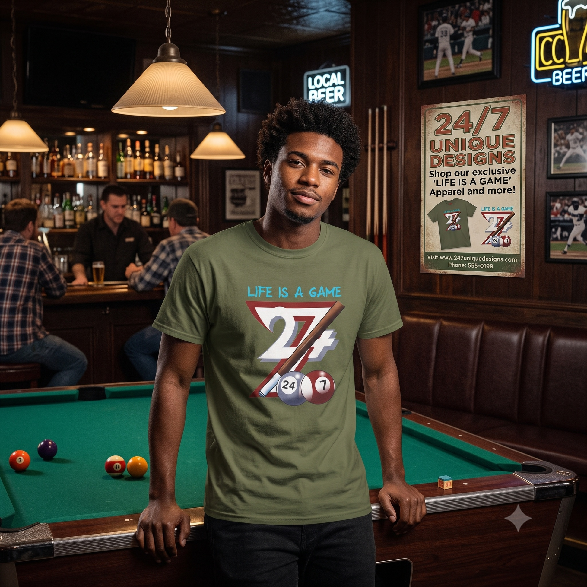 Young man smiling confidently beside a green pool table in a classic pub setting, wearing the army green billiards graphic tee with a 24/7 Unique Designs vintage poster on the wall behind him.