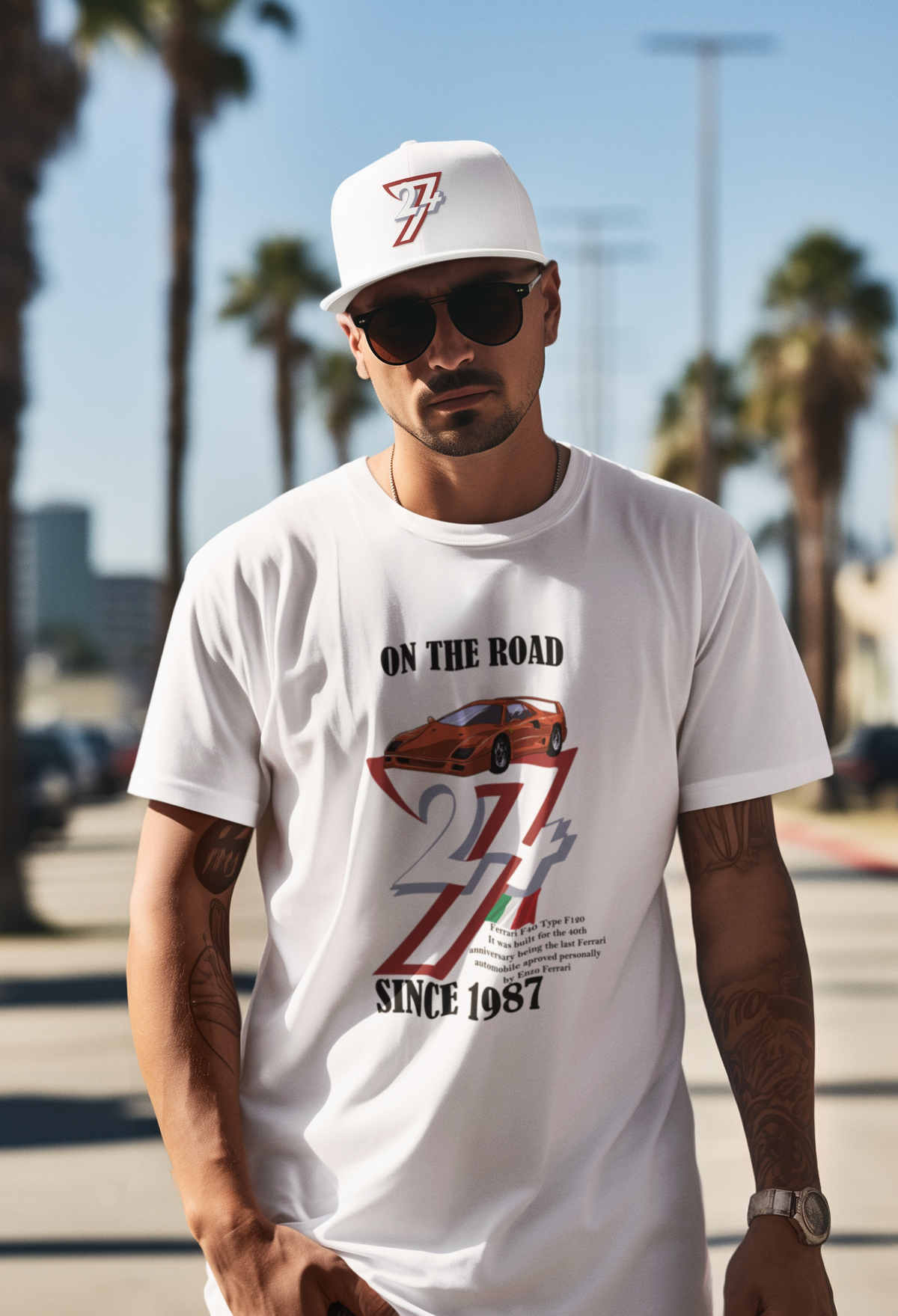 Stylish man wearing sunglasses and a white dad hat with a 24/7 logo standing outdoors on a sunny palm-tree-lined street, modeling the crisp white 1987 Vintage Ferrari F40 Tee.