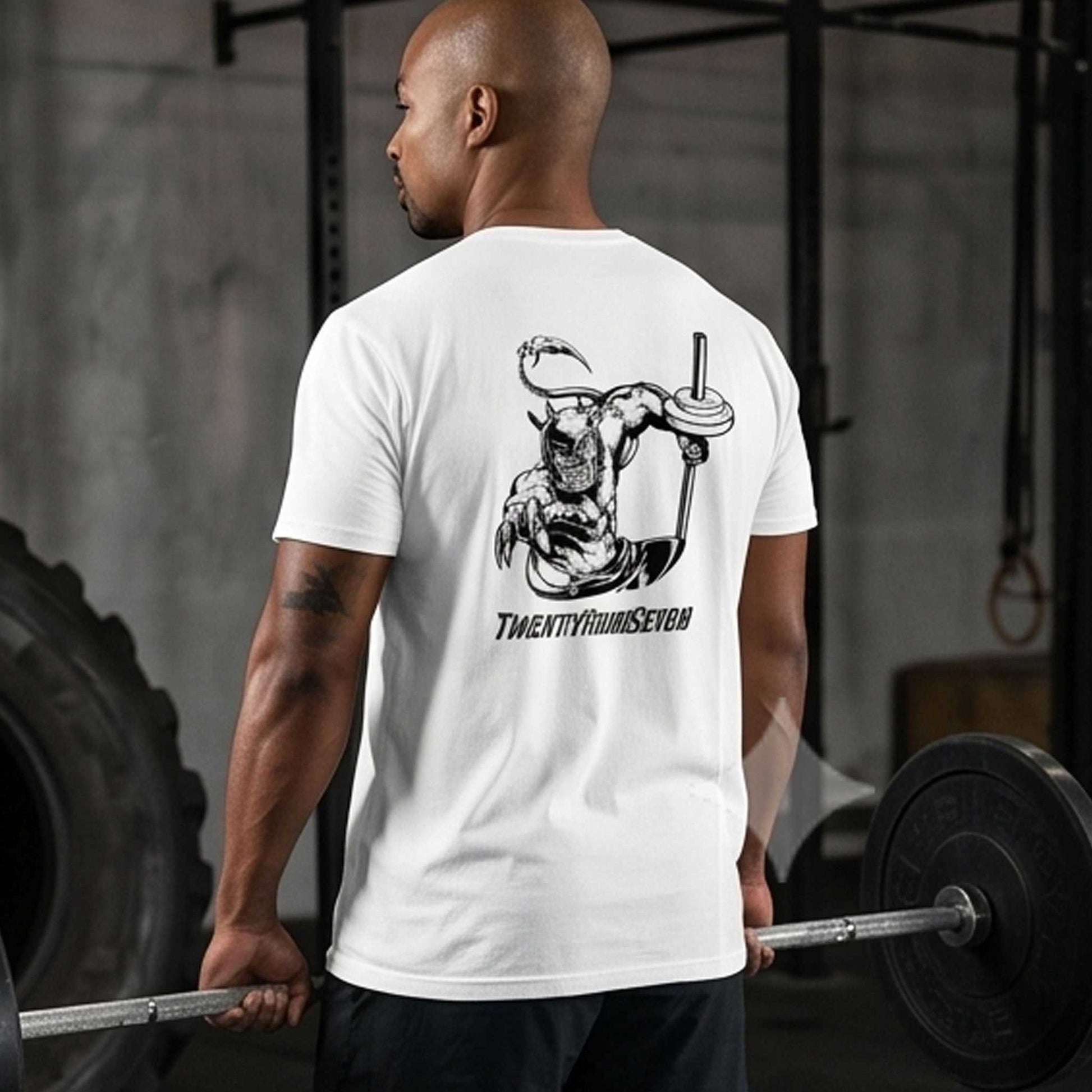 Muscular male model seen from the back wearing the white unisex bodybuilding graphic tee, holding a barbell in a gym setting to perfectly showcase the monochrome hand-drawn Dablo comic graphic.