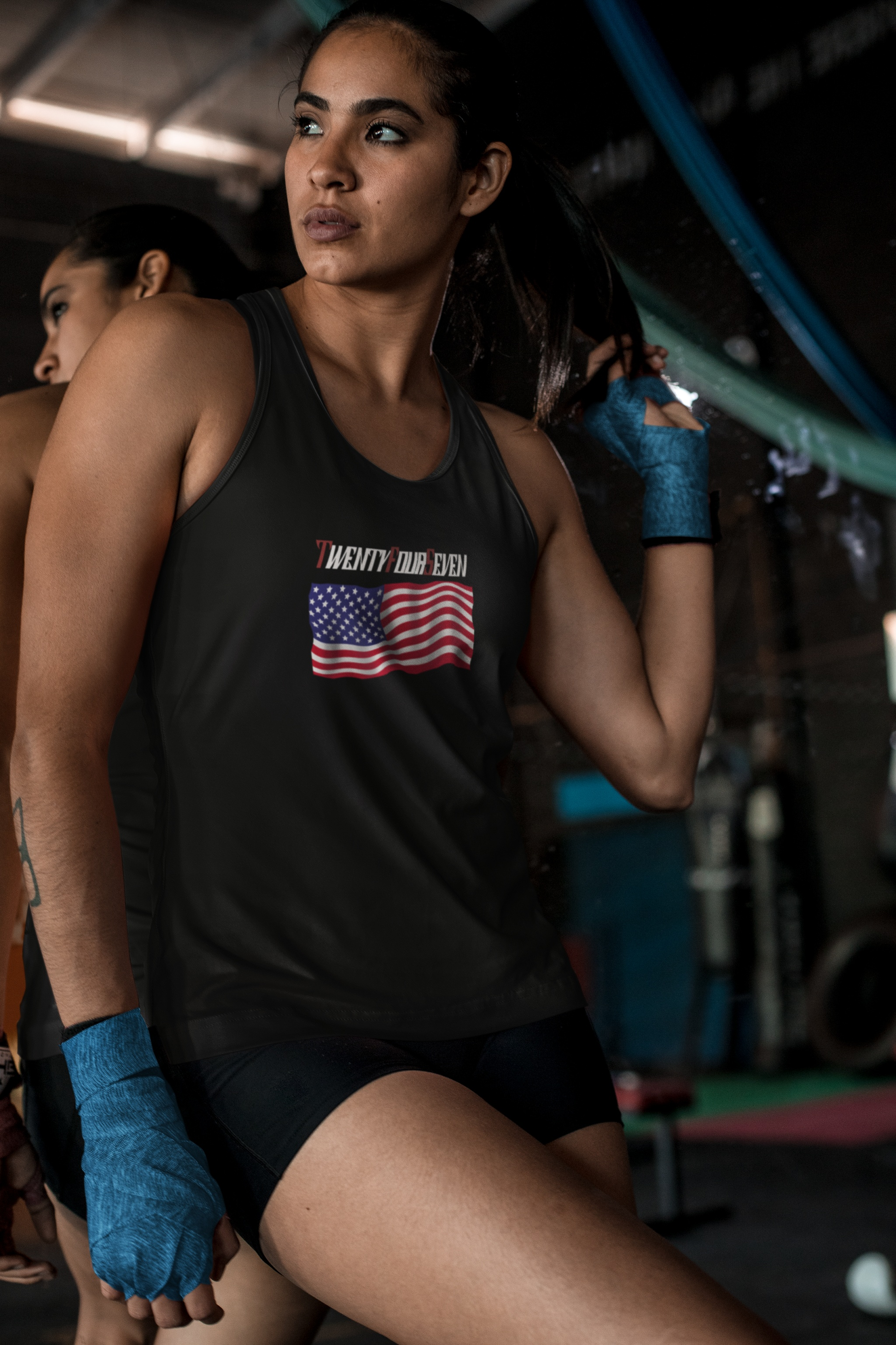 Female model wearing a black comfortable TwentyFourSeven US flag tank top in a lifestyle setting.