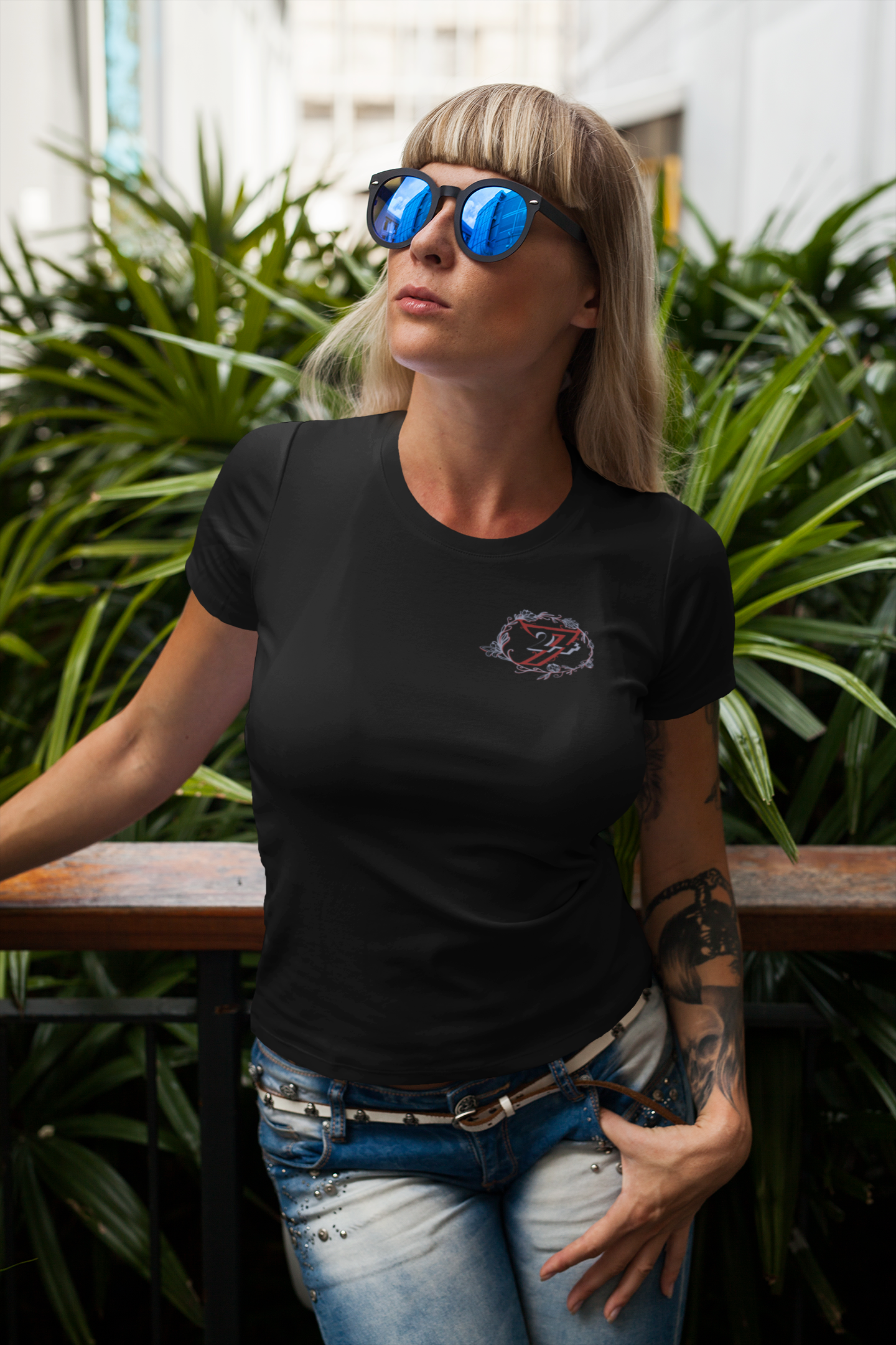 Woman modeling a sleek black everyday t-shirt with an understated left breast floral design.