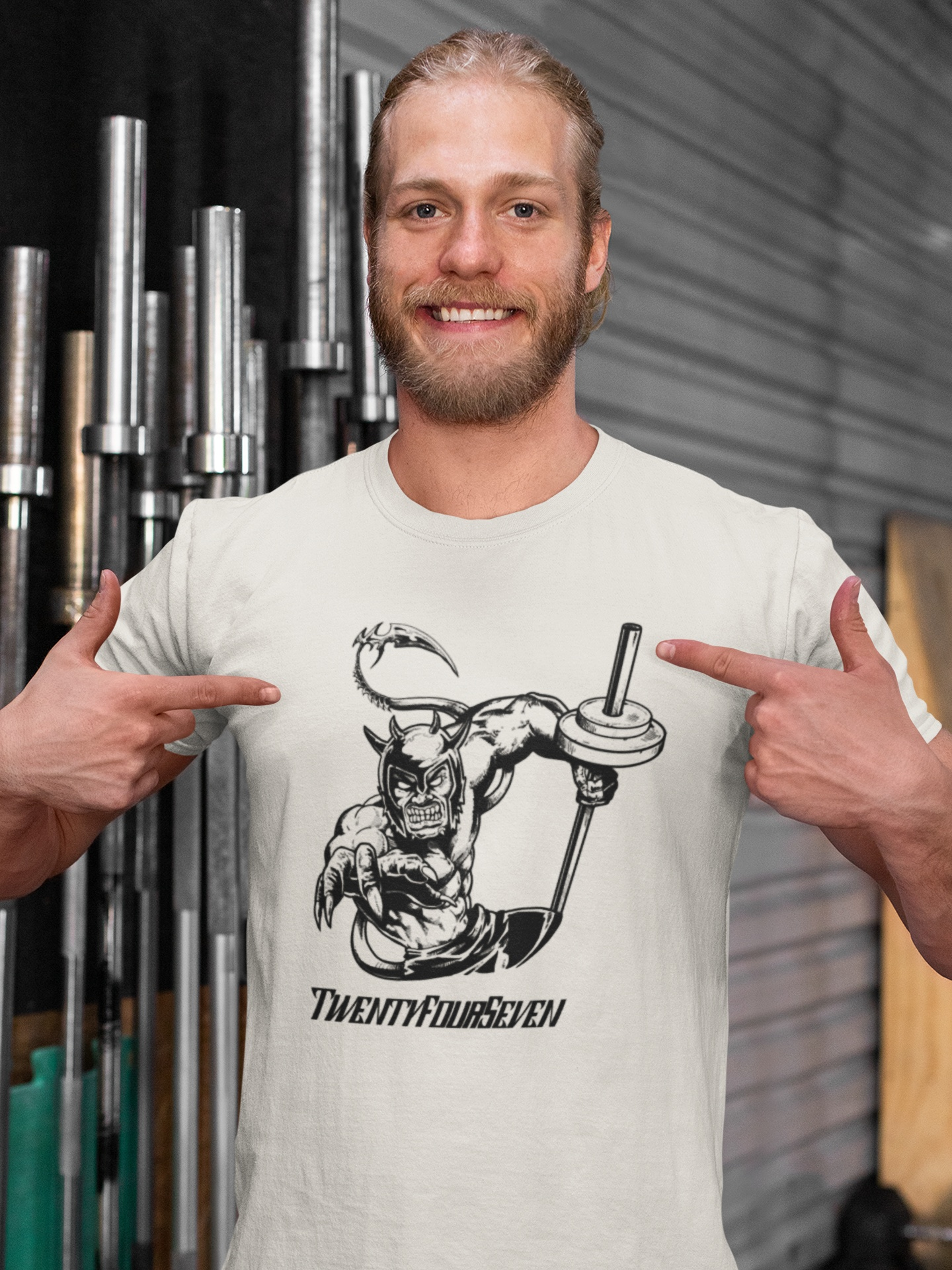 Muscular male model wearing the white fantasy workout shirt, standing confidently in a gym in front of power bars to showcase the vibrant front ALK comic graphic.