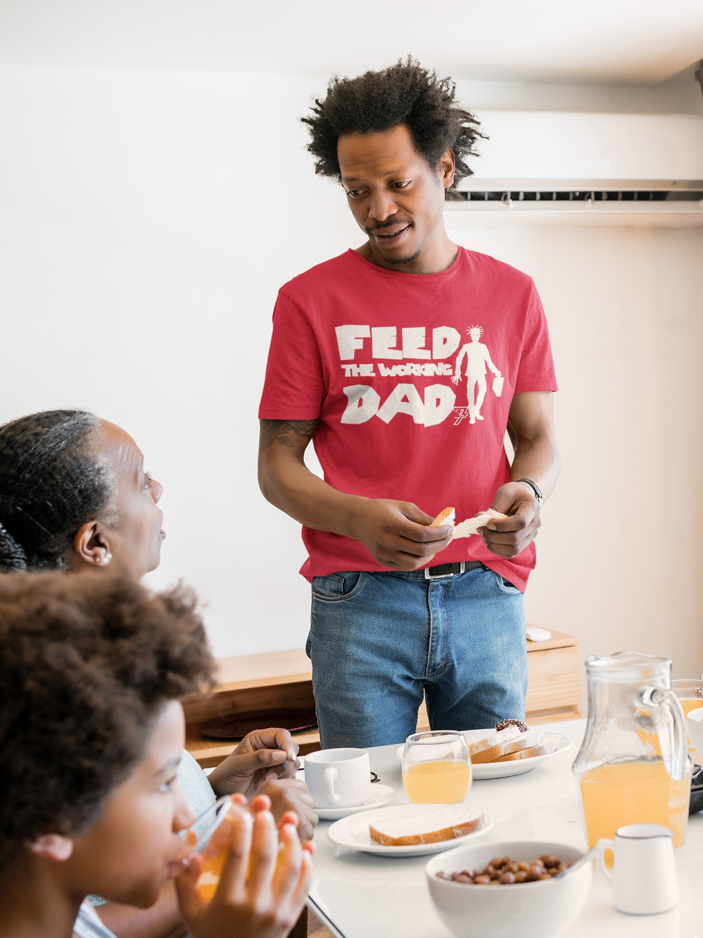 Male model styling the red funny office zombie dad tee with white contrast print while holding bread at a family dinner table, demonstrating a special Christmas gift idea.