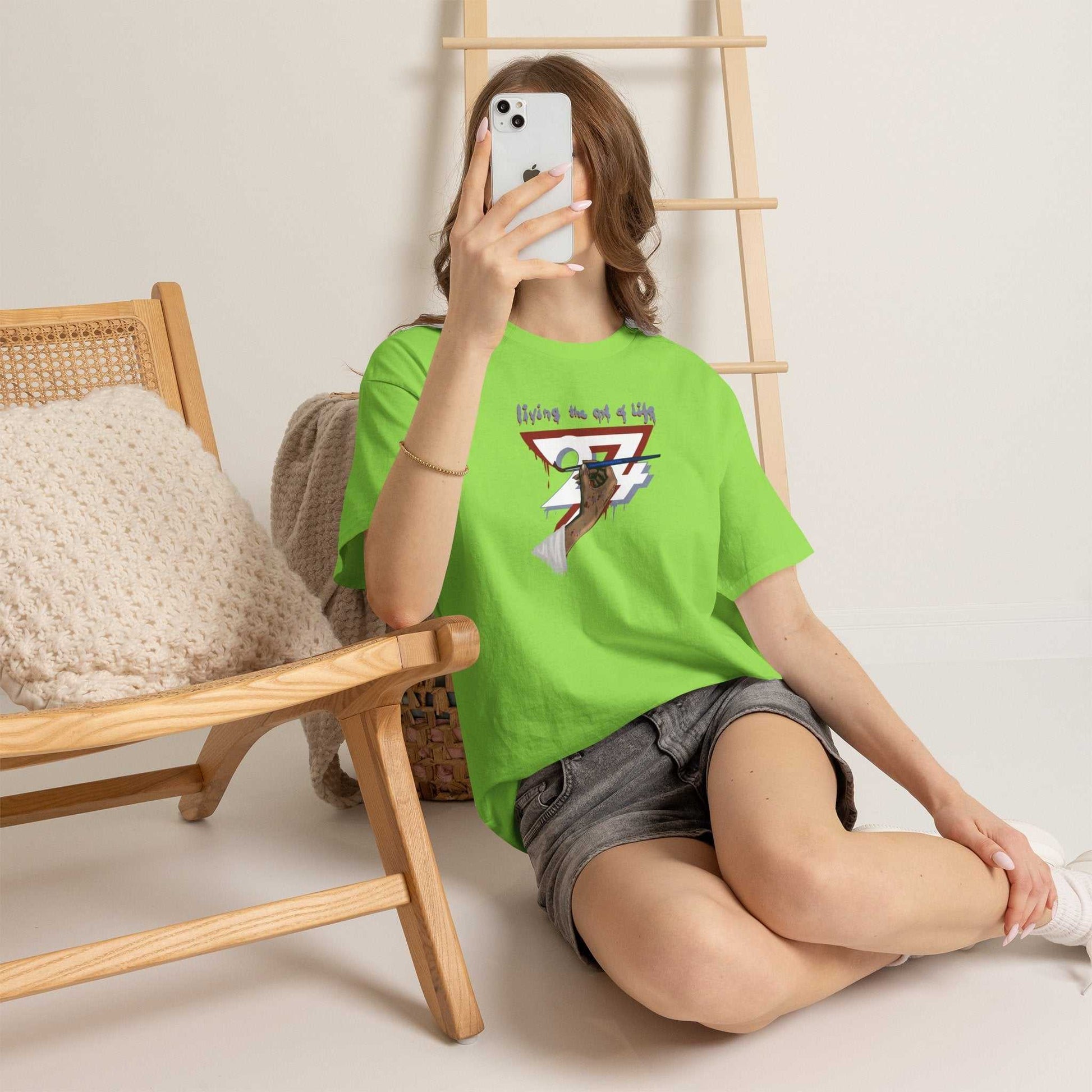 Female model sitting on the floor taking a mirror selfie wearing the neon green creative streetwear for women, relaxing casually next to a wooden chair.