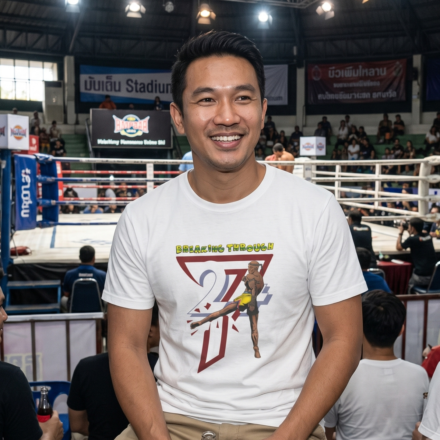 Smiling male fan sitting ringside at an authentic Muay Thai stadium, wearing the white martial arts streetwear graphic tee to showcase its casual, comfortable fit and vibrant 90s comic art.