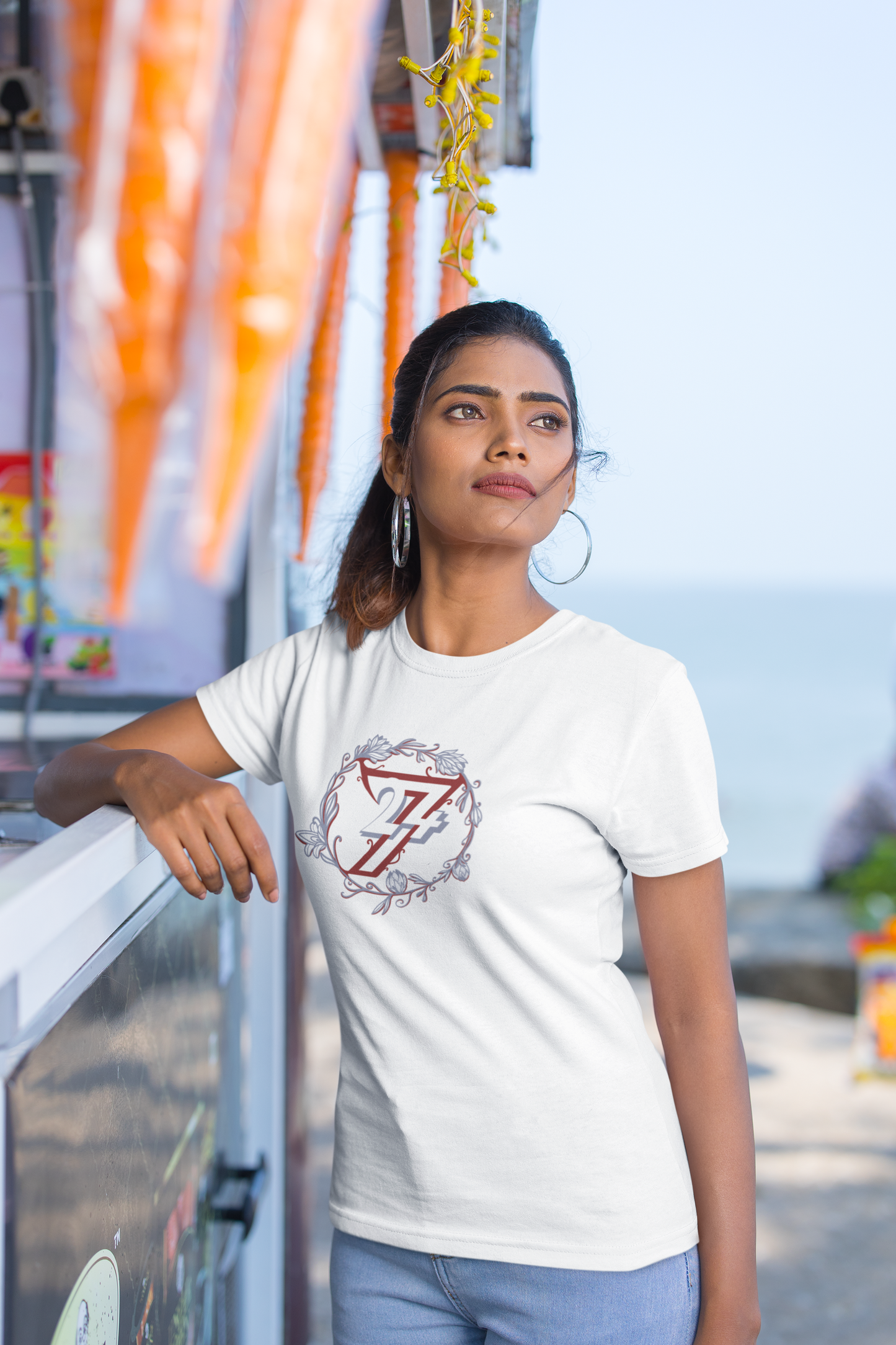 Woman modeling a crisp white premium t-shirt with a circular floral wreath graphic.