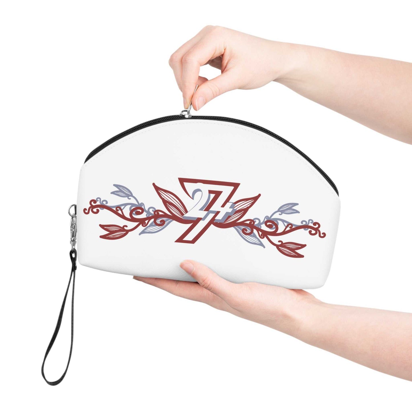 A person's hands holding the white vegan leather cosmetic pouch, gently pulling the top zipper closed to demonstrate the bag's convenient size and the attached black wristlet strap.