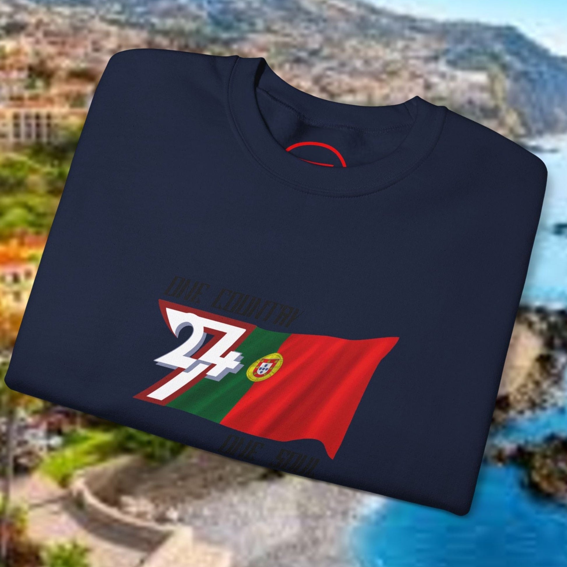Folded navy Portugal Flag Sweatshirt with vibrant hand-drawn design on scenic coastal background