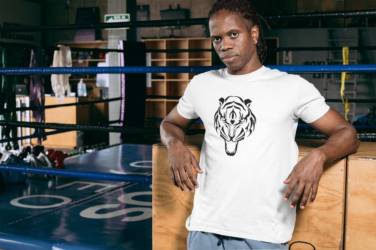Person wearing a white t-shirt with a tiger logo in a boxing ring.