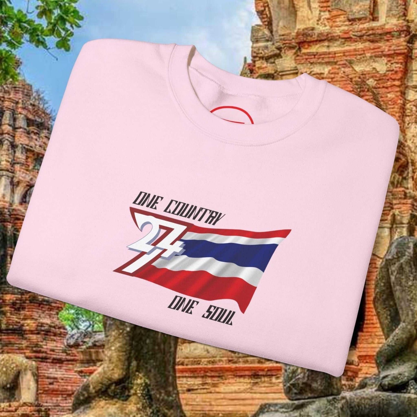 Folded pink Thailand flag sweatshirt with "One Country One Soul" text and Thai flag graphic on the front, set against a historic temple background