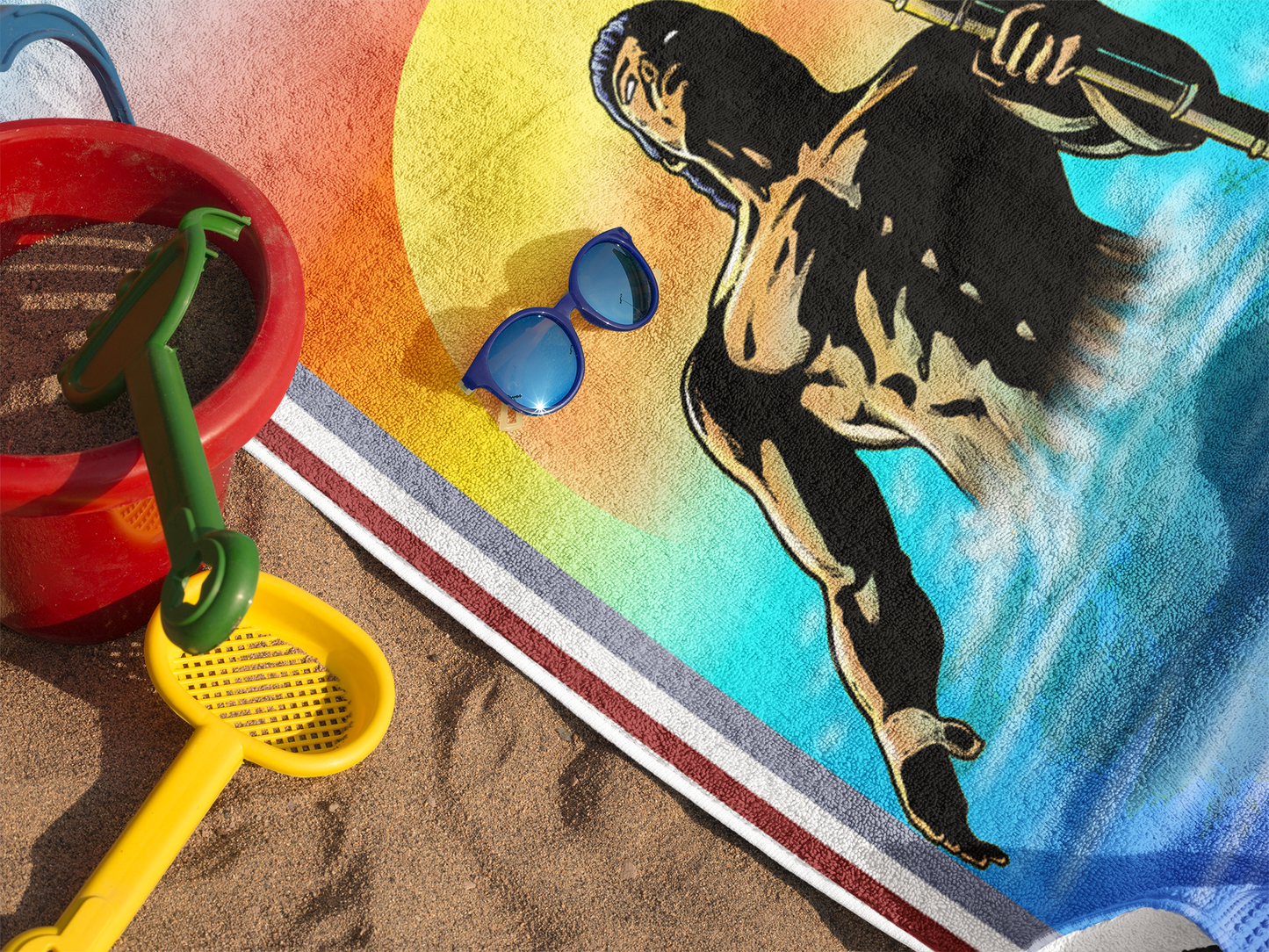 Close-up of a pool towel showing a retro comic book style Greek God graphic with a yellow and orange sunset.