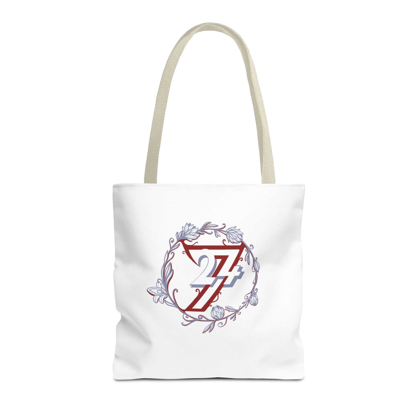A white canvas tote bag with beige shoulder straps, featuring a central graphic of a red stylized 24/7 monogram inside a circular floral wreath with light blue accents.