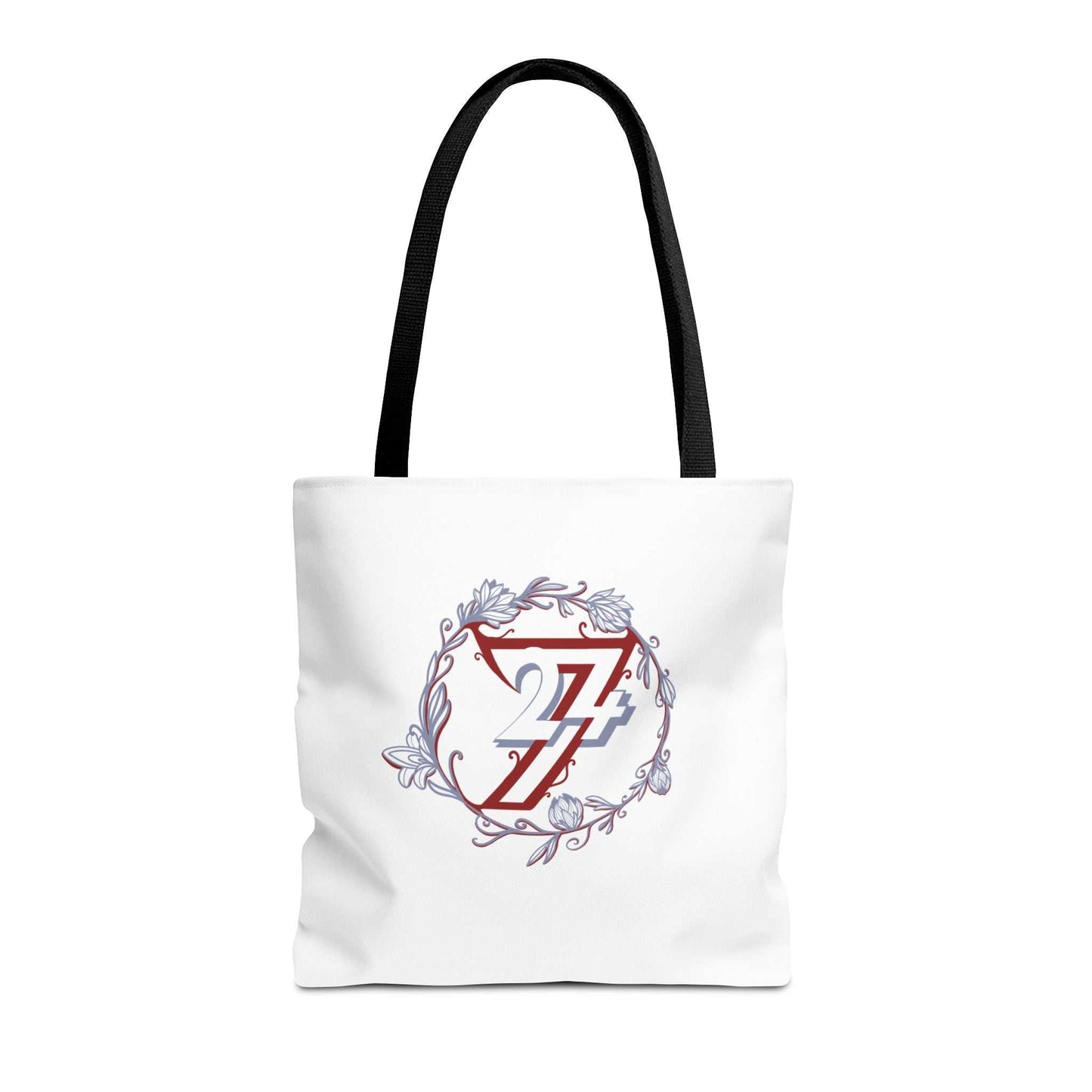 A white canvas floral tote bag with black shoulder straps, featuring a central graphic of a red stylized 24/7 monogram inside a circular floral wreath with light blue accents.