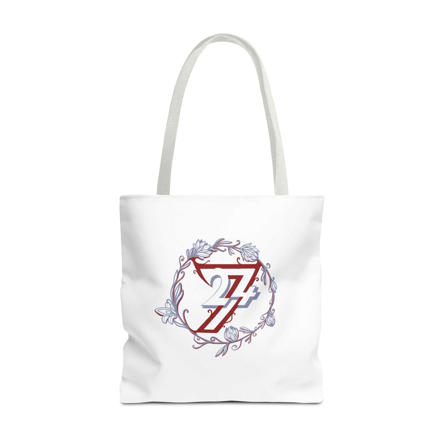 A white large floral canvas tote bag with two shoulder straps, featuring a central graphic of a red stylized letter 24/7 logo inside a white shield, surrounded by a circular floral wreath in muted blue-gray tones.