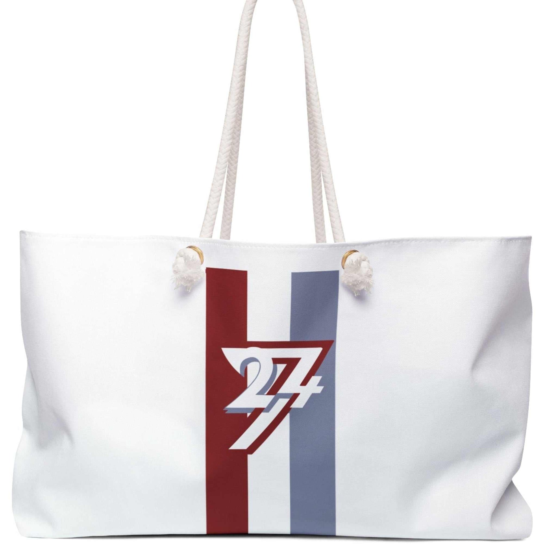 Front view of the white oversized weekender tote bag featuring the 24/7 racing stripe graphic, thick cotton rope handles, and gold grommets, displayed on a clean white background.