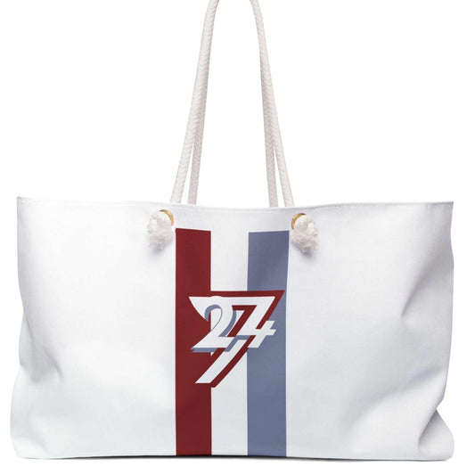 Front view of the white oversized weekender tote bag featuring the 24/7 racing stripe graphic, thick cotton rope handles, and gold grommets, displayed on a clean white background.