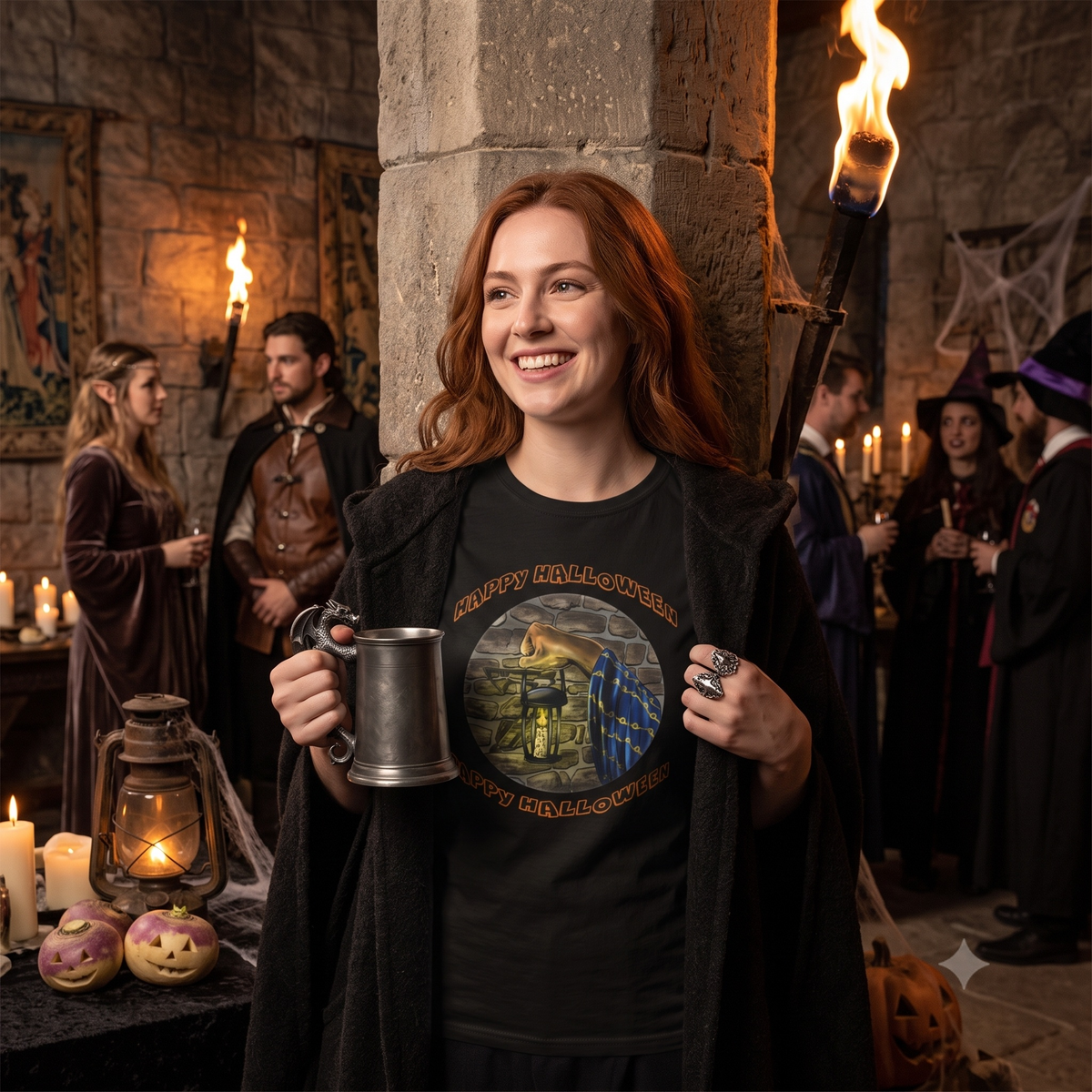 Happy woman standing in a stone castle dungeon holding a metal tankard, wearing a black cloak over the black Halloween wizard graphic tee at a fantasy-themed gathering.