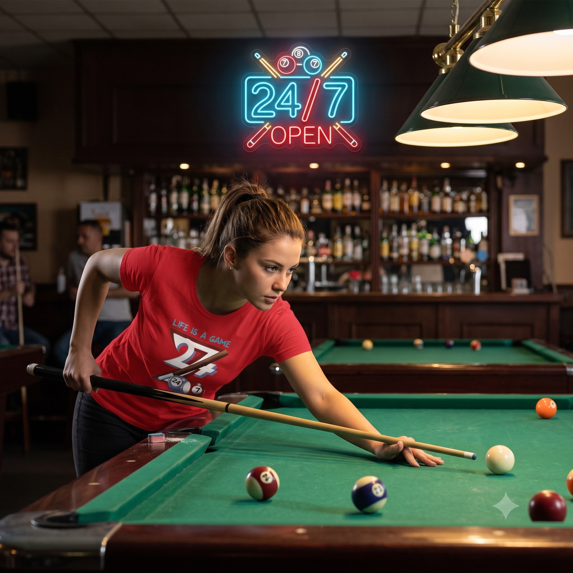 Focused young woman lining up a shot at a billiards table in a warmly lit bar, wearing a red Life is a Game t-shirt beneath a glowing neon 24/7 Open sign.