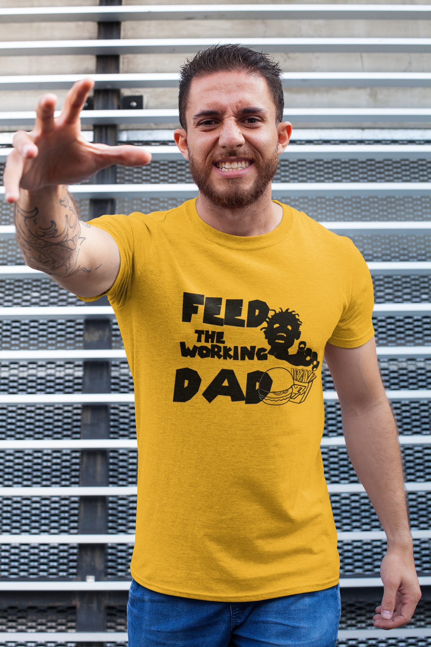 Man wearing a gold yellow zombie dad graphic t-shirt, standing against a metal background